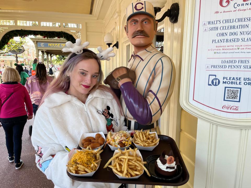 jenna posing with a baseball player statue at casey's corner and carrying a tray of food