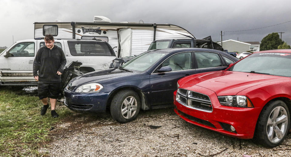 Sean Hagan surveys the damage from a tornado in his family's driveway where a camper trailer was pushed up into the air, damaging several cars, Saturday, Sept. 8, 2018, in Stanley, Ky. There was moderate to severe damage to several homes, trees broken and vehicles pushed together. (Greg Eans/The Messenger-Inquirer via AP)
