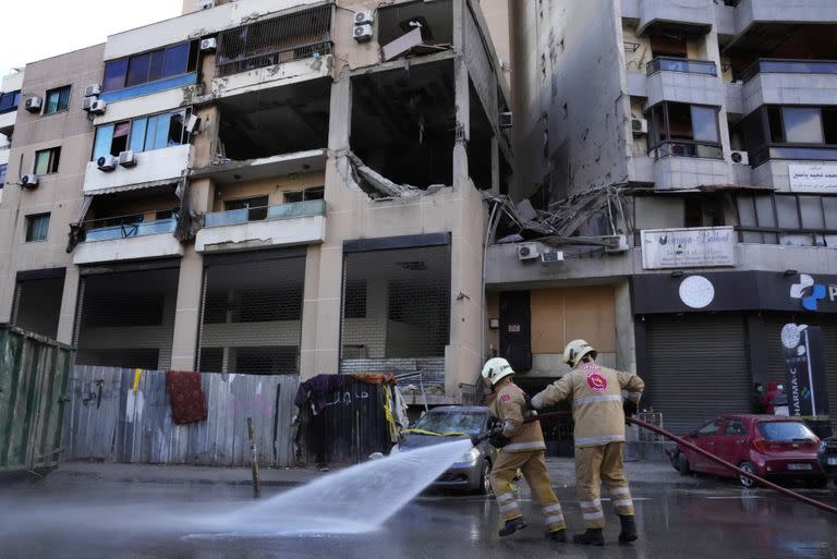 Operarios de las fuerzas de defensa civil limpian la calle frente a un edificio residencial donde un presunto ataque israelí mató en la víspera a un alto cargo político de Hamas, Saleh Al-Arouri, en un suburbio del sur de Beirut, que es un feudo del grupo Hezbollah, en el Líbano, el 3 de enero de 2024. (AP Foto/Hussein Malla)