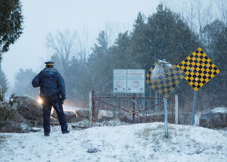 An RCMP officer waits as a group that claimed to be from Syria arrives at the U.S.-Canada border in Hemmingford, Quebec. REUTERS/Dario Ayala