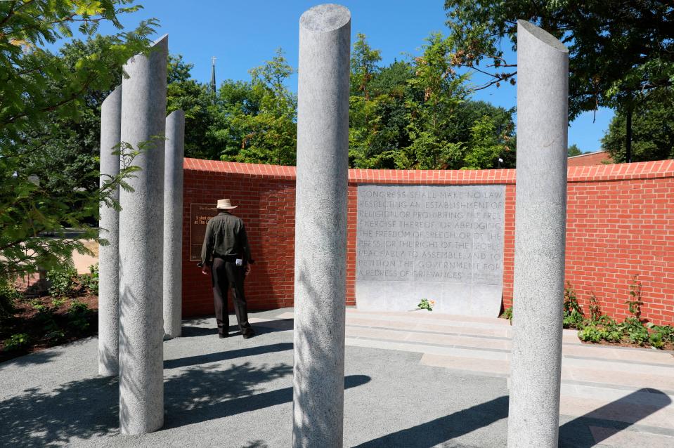 A visitor stands by a new memorial dedicated to the five people who died in the mass shooting at the Capital Gazette three years ago, Monday, June 28, 2021 in Annapolis, Md. The five pillars honor Rebecca Smith, Wendi Winters, Gerald Fischman, Rob Hiaasen, and John McNamara who died in the attack. The memorial includes the First Amendment in a panel. (AP Photo/Brian Witte)