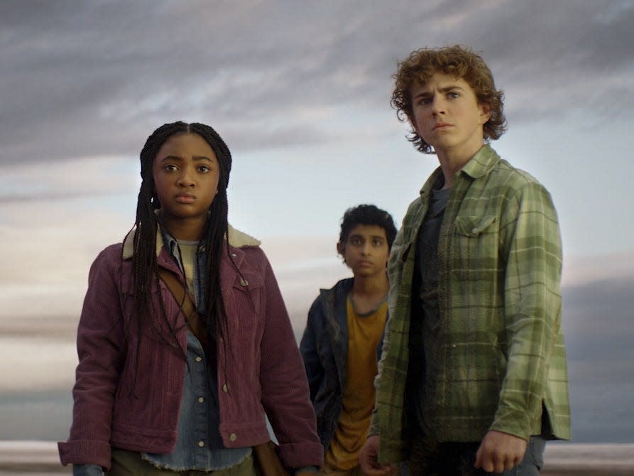 leah sava jeffries, aryan simhadri, and walker scobell in percy jackson and the olympians. they're three children, standing together against a cloudy sky, looking serious