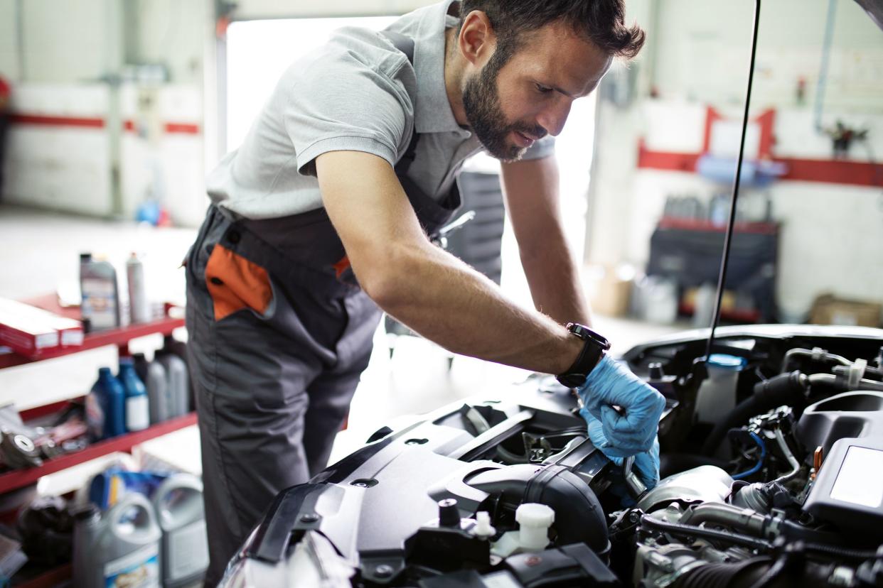 mechanic looking under hood of car