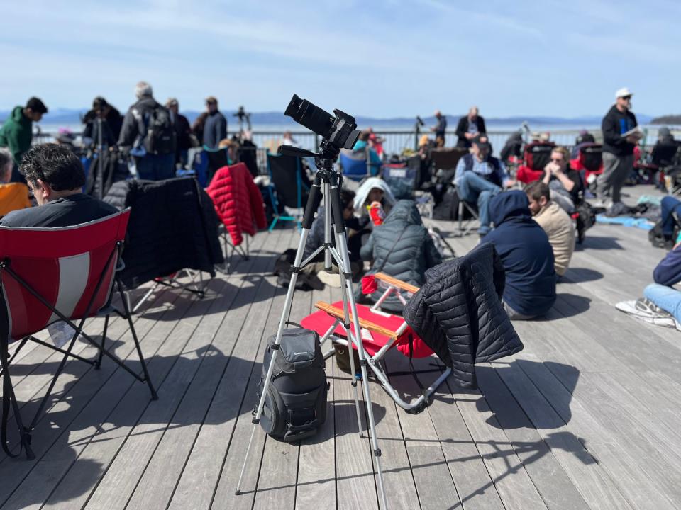 A DSLR stands on a tripod with a crowd in the background