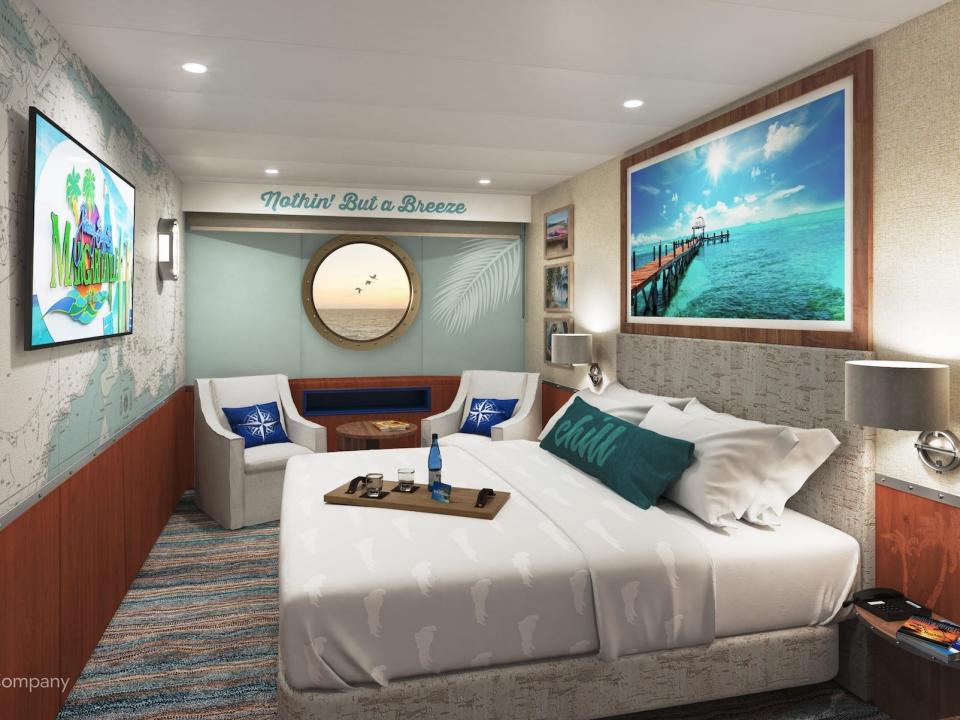 A stateroom aboard the Margaritaville Paradise with a bed, window, and chairs