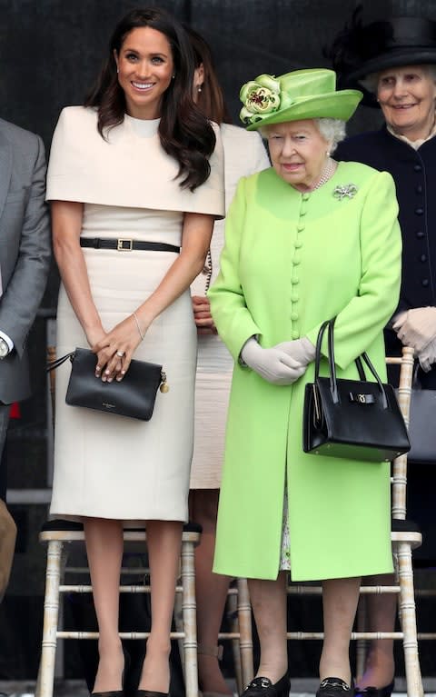 The Duchess wore a knee-length Givenchy dress with a shoulder cuff and black clutch, while the Queen dressed in a green outfit for Grenfell - Credit: PA 