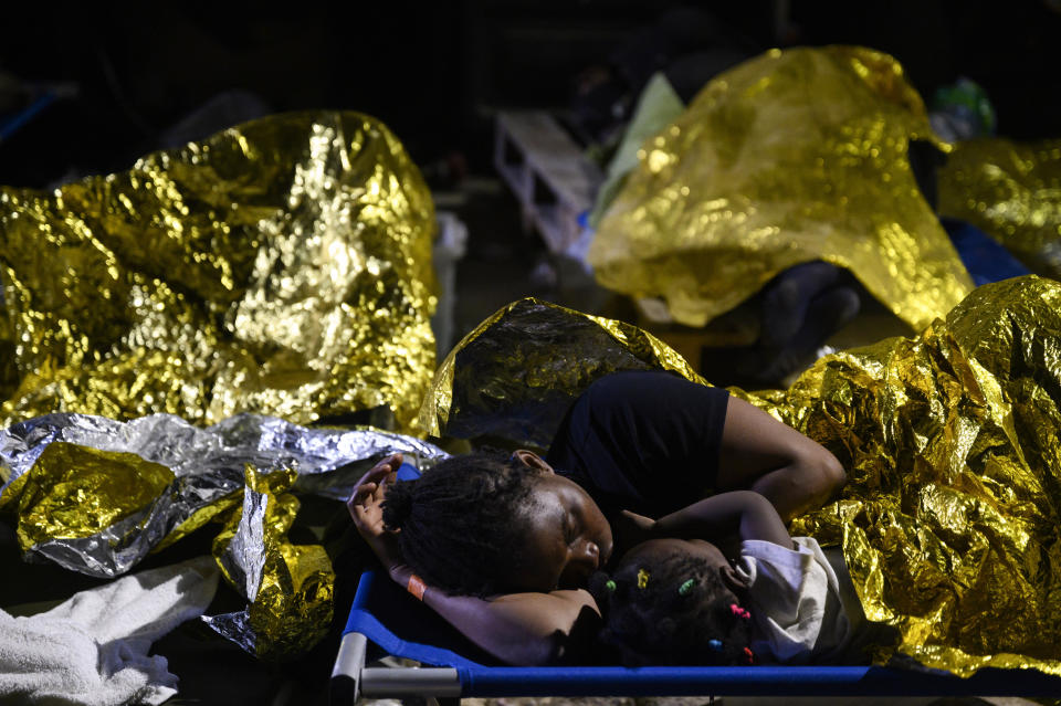 FILE - A woman and a child sleep outside the Lampedusa's migrant reception center, Sicily, early Thursday Sept. 14, 2023. Thousands of migrants and refugees have landed on the Italian island of Lampedusa this week after crossing the Mediterranean Sea on small unseaworthy boats from Tunisia, overwhelming local authorities and aid organizations . (AP Photo/Valeria Ferraro, file )