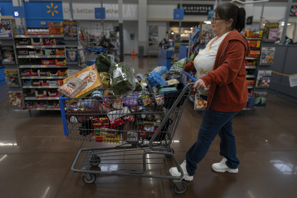 Jodi Ferdinandsen, a client of Jesse Johnson of the Family Resource Center, pushes her grocery cart through Walmart in Findlay, Ohio, Thursday, Oct. 12, 2023. The Family Resource Center provides peer support workers to help clients during early recovery. (AP Photo/Carolyn Kaster)