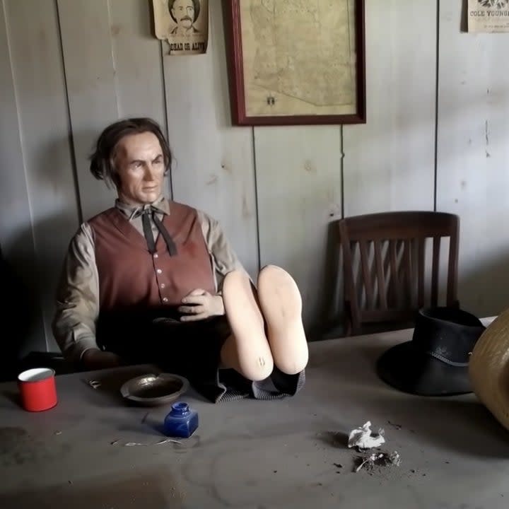 An old west dummy sits with its feet on a table