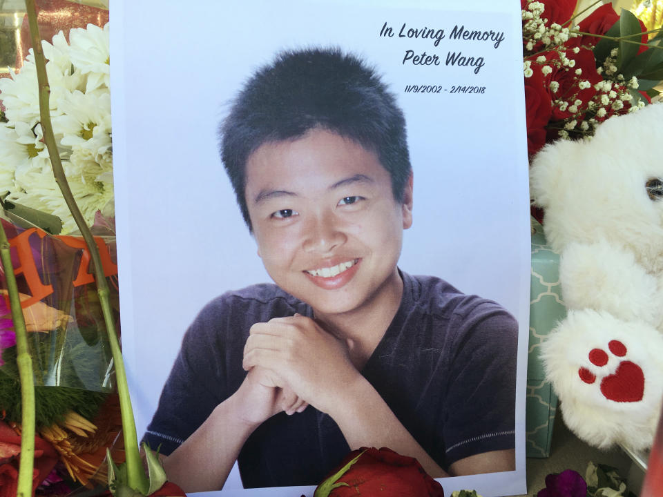 <p>Student Peter Wang is seen in this photo near a memorial in Parkland, Fla., Friday, Feb. 16, 2018. (Photo: Allen Breed/AP)<br>Peter Wang died wearing his gray ROTC shirt and was last seen holding a door open for other students, his cousins Lin Chen and Aaron Chen told local news outlets. “He doesn’t care about popularity. He always liked to cheer people up. He is like the big brother everyone wished they had,” said Lin Chen. She told the Sun Sentinel that Wang had two brothers, ages 11 and 5, and his parents, too upset to talk, own a restaurant in West Palm Beach, Fla. They had planned to celebrate Chinese New Year’s eve Thursday. (AP) </p>
