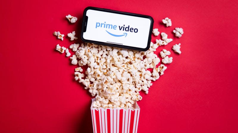 A box of popcorn on its side with popcorn and a phone reading "prime video" spilling out of it.