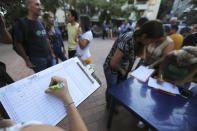 In this Feb. 19. 2019 photo, people fill forms to joint to the group of volunteers that will help to introduce humanitarian aid into Venezuela, during a meeting to recruit volunteers, at a square in Caracas, Venezuela. The volunteers anticipate running into roadblocks by soldiers who remain loyal to Maduro. They know that their chances of breaking through at first are slim, but they’re undaunted. (AP Photo/Fernando Llano)