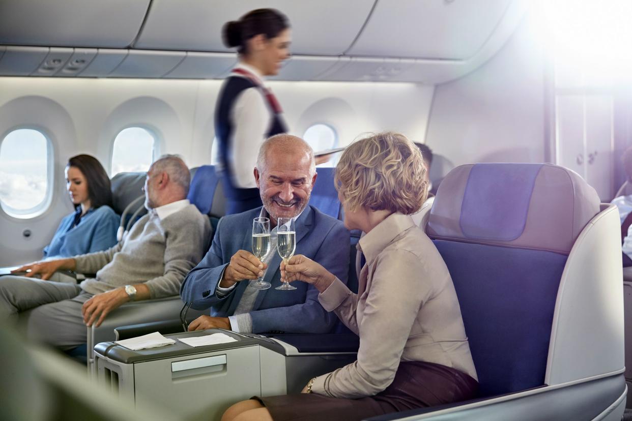 mature couple toasting champagne glasses in first class on airplane