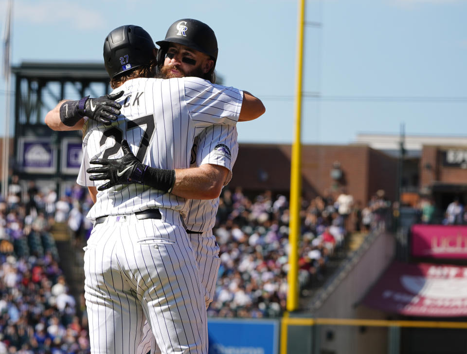 Colorado Rockies pinch-runner Jordan Beck, front, hugs Charlie Blackmon as he is replaced on first base after his single in his final at-bat in the third inning of a baseball game against the Los Angeles Dodgers, Sunday, Sept. 29, 2024, in Denver. (AP Photo/David Zalubowski)