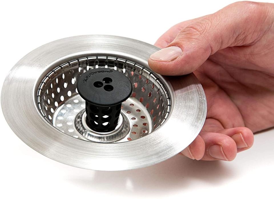 Hand placing a mesh kitchen sink strainer into the sink's drain