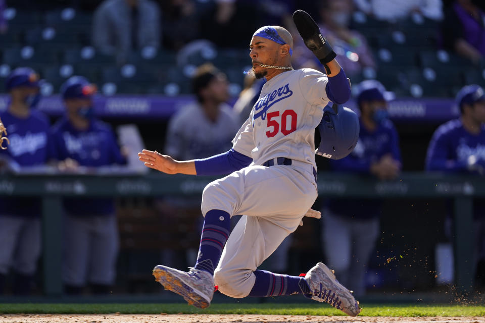 Los Angeles Dodgers' Mookie Betts slides across home plate to score on a single by Max Muncy off Colorado Rockies relief pitcher Chi Chi Gonzalez in the sixth inning of a baseball game Thursday, April 1, 2021, in Denver. (AP Photo/David Zalubowski)