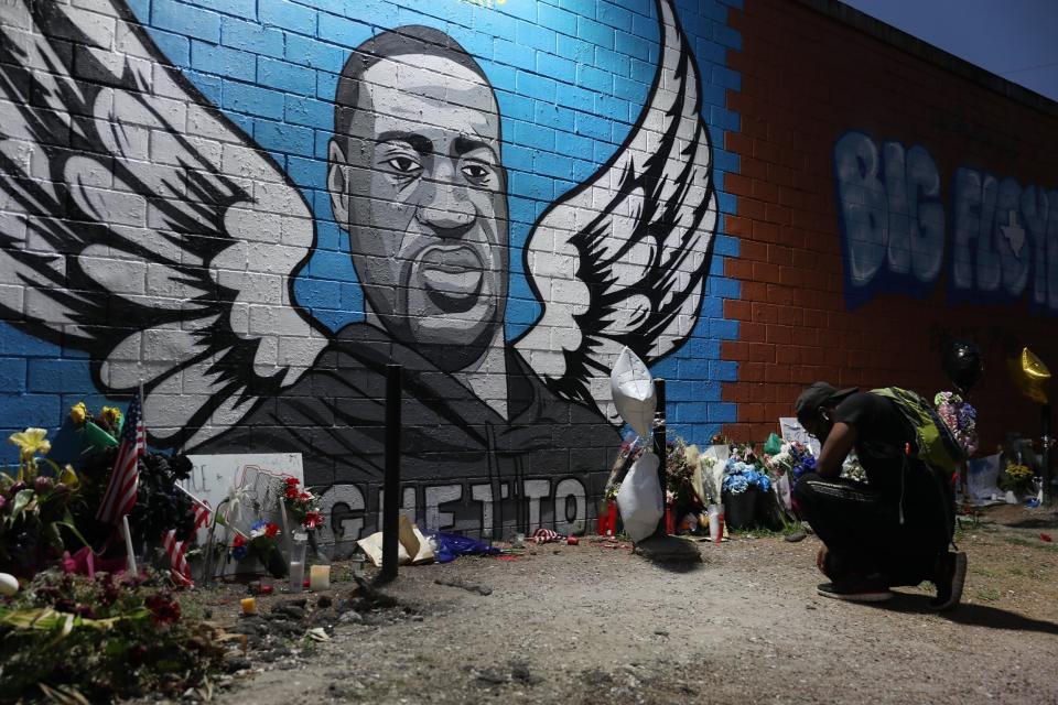 Joshua Broussard kneels in front of a memorial and mural that honors George Floyd at the Scott Food Mart corner store in Houston's Third Ward (Getty Images)