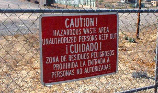 A caution hazardous waste sign in front of a site