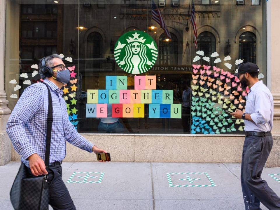 Two people wearing face masks walking outside a Starbucks store in New York City.