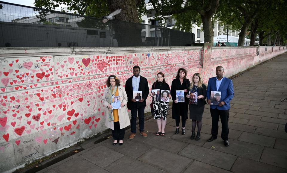 <p>Members of the Covid-19 Bereaved Families for Justice group, from left, Deborah Doyle, Lobby Akinnola, Hannah Brady, Fran Hall, Jo Goodman and Charlie Williams, hold photos of those who lost their lives to coronavirus, as they pose for a photograph in front of the National Covid Memorial Wall, at the embankment on the south side of the River Thames in London on September 28, 2021. (Photo by DANIEL LEAL-OLIVAS / AFP) (Photo by DANIEL LEAL-OLIVAS/AFP via Getty Images)</p>
