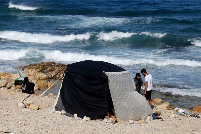 A couple stands near a makeshift tent they erected on the Beirut coast after fleeing heavy Israeli air raids on Beirut southern suburb. Thousands of Lebanese and Syrian nationals fled south Lebanon and Beirut southern suburb following heavy Israeli air raids. Marwan Naamani/dpa