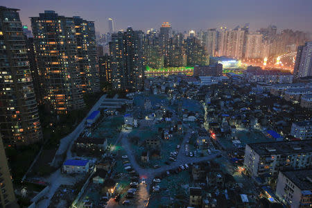 A night view of the old houses surrounded by new apartment buildings at Guangfuli neighbourhood in Shanghai, China, April 10, 2016. REUTERS/Aly Song