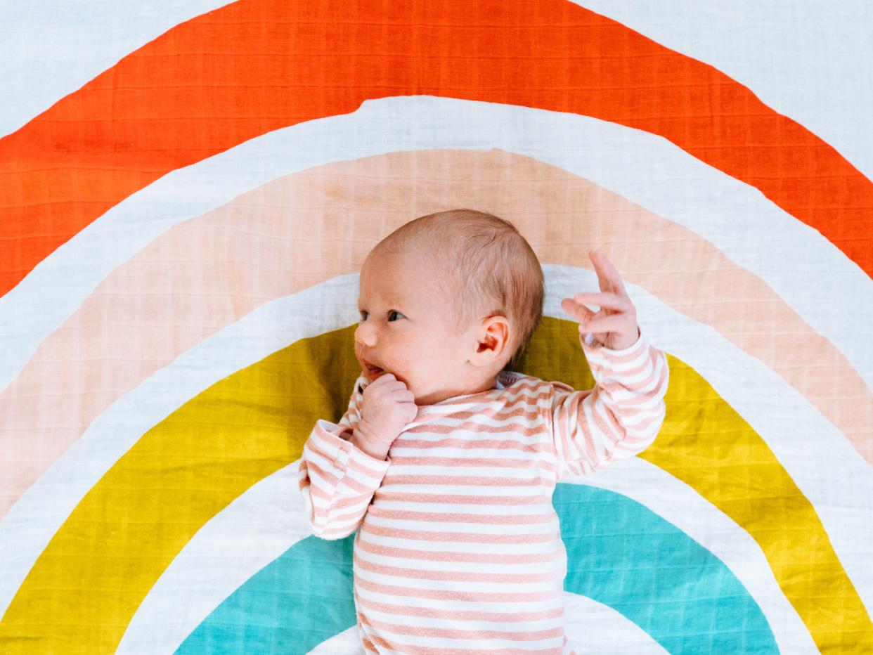 View from above of a newborn baby on a rainbow colored blanket