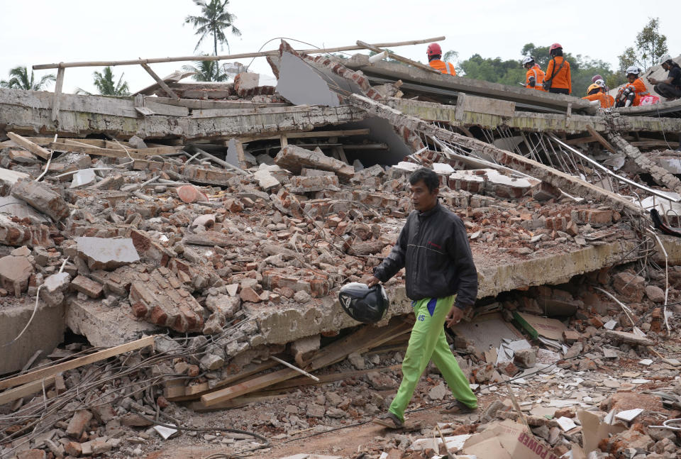 Enjot, 45, who lost his house and few relatives, walks past the rubble of a building collapsed in Monday's earthquake in Cianjur, West Java, Indonesia Tuesday, Nov. 22, 2022. Rescuers on Tuesday struggled to find more bodies from the rubble of homes and buildings toppled by an earthquake that killed a number of people and injured hundreds on Indonesia's main island of Java. (AP Photo/Tatan Syuflana)