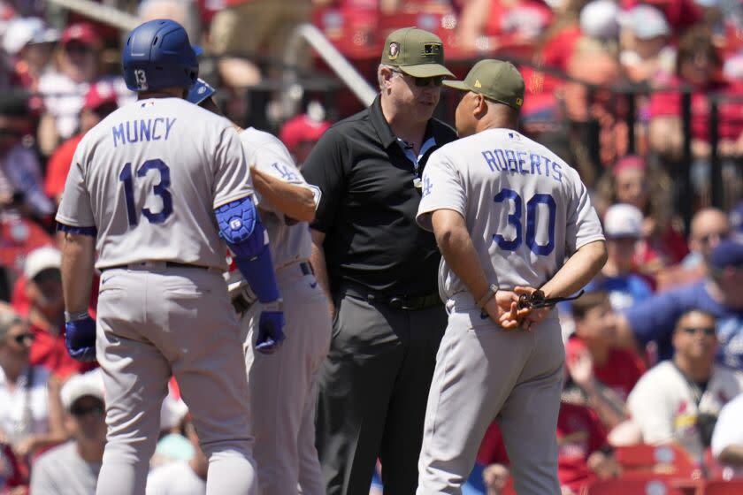 Los Angeles Dodgers manager Dave Roberts (30) talks with third base umpire Paul Emmel.