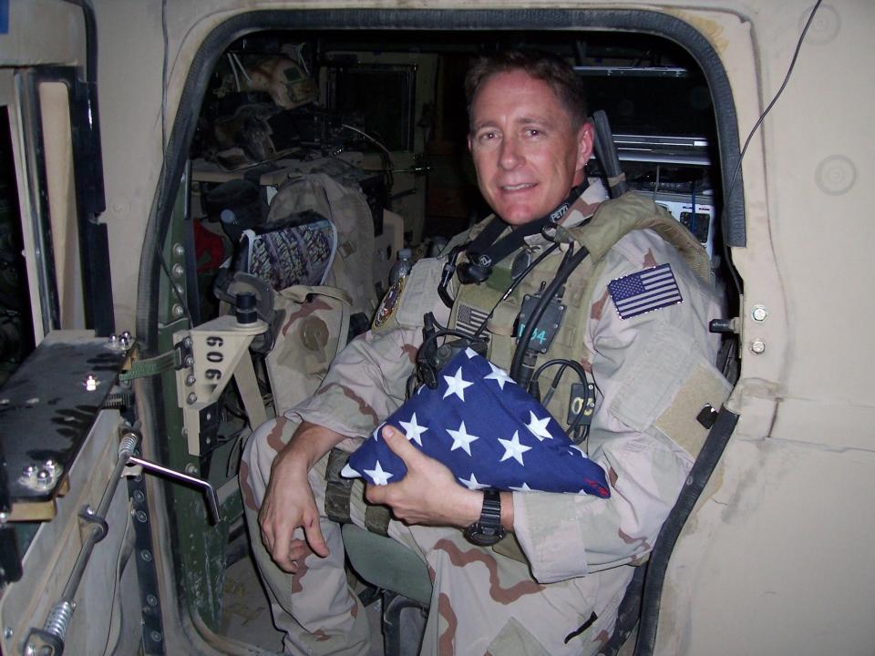 U.S. Navy combat veteran Ken McDonald is pictured with a memorial flag to be carried on a mission in Baghdad, Iraq.