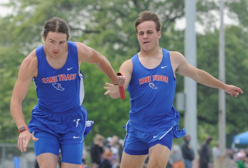 Zane Trace's Riley Hartsaugh (right) hands the baton off to teammate Charley Clyne during the boys 4x200 meter relay in the Division II district track and field meet at Washington High School on May 20, 2023.