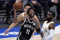 Brooklyn Nets guard Kyrie Irving (11) drives to the basket for a shot past Dallas Mavericks guard Josh Green, rear, and Tim Hardaway Jr., right, in the second half of an NBA basketball game in Dallas, Thursday, May 6, 2021. (AP Photo/Tony Gutierrez)