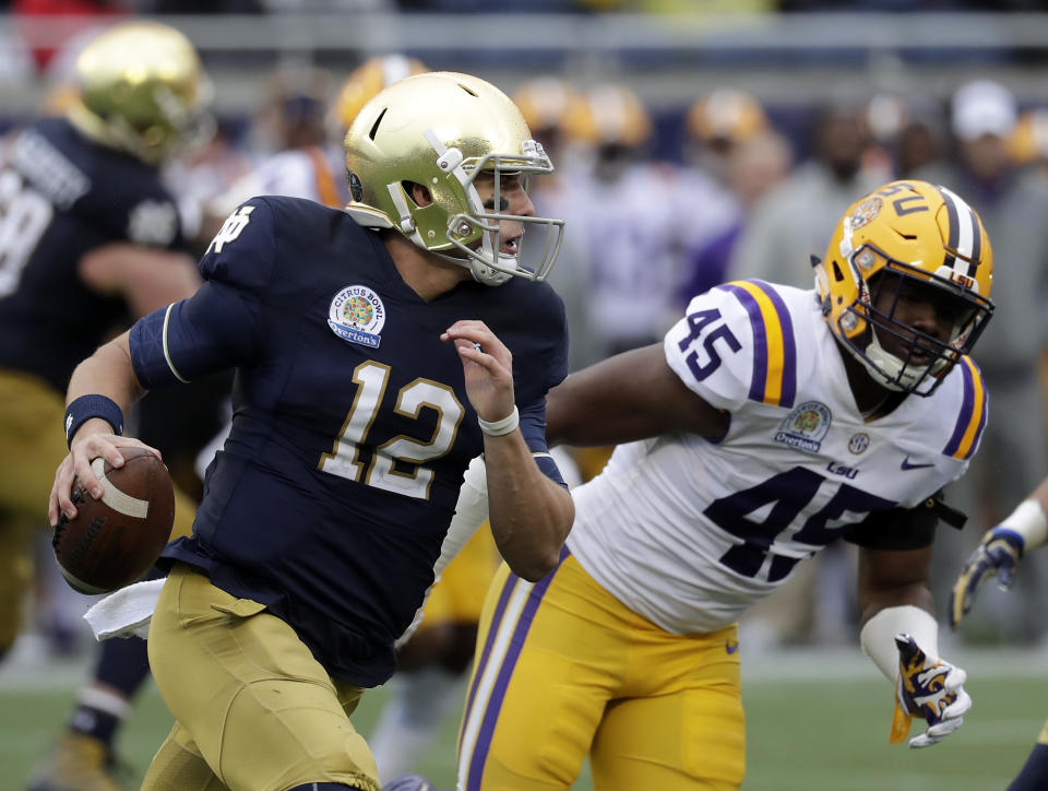 Notre Dame quarterback Ian Book (12) shambles for yardage past LSU linebacker Michael Divinity Jr. (45) during the first half of the Citrus Bowl NCAA college football game, Monday, Jan. 1, 2018, in Orlando, Fla. (AP Photo/John Raoux)