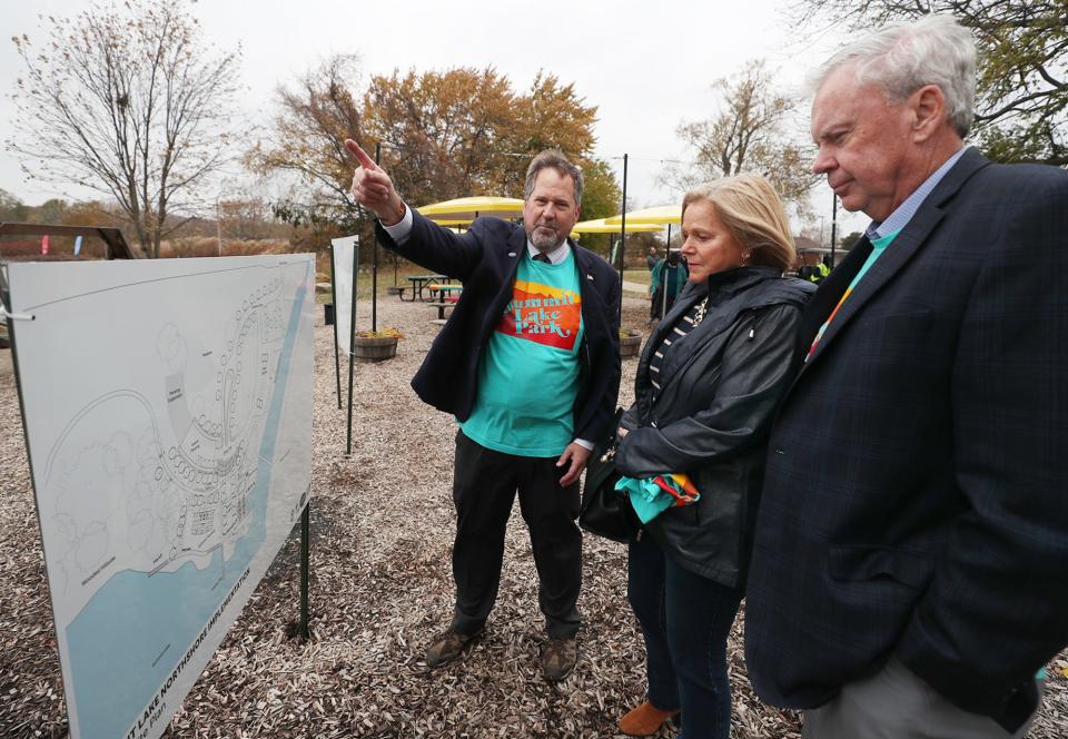 Dan Rice, CEO of Ohio and Erie Canalway Coalition, gestures to Summit Lake as he discusses the project with Pam Loughry and Bill Considine in Akron.