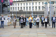 Family members arrive for the inquest into holding photos of the victims of the Ballymurphy shooting, in Belfast, Northern Ireland, Tuesday May 11, 2021. The findings of the inquest into the deaths of 10 people during an army operation in August 1971 is due to be published on Tuesday. (AP Photo/Peter Morrison)