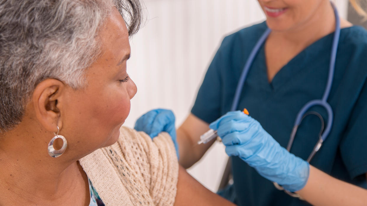  Nurse gives a vaccine to an older woman at a clinic. 