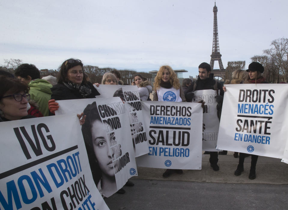 Demonstrators holds placard near the Eiffel tower during a really to protest against the new abortion law in Spain, in Paris, Saturday Feb. 1, 2014. Spain's conservative government approved tight restrictions on abortion, allowing the practice only in the case of rape or when there is a serious health risk to the mother or fetus. Placards read from left, "induced abortion is my right, to choose not die, duty threatened health in danger, right in danger health in danger". (AP Photo/Michel Euler)