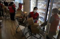 In this Tuesday, Feb. 18, 2020, photo, workers at the 7Fresh supermarket restock the fridge in Beijing. Stores that offer online purchases are enjoying brisk sales as residents avoid going out during the current viral outbreak with authorities last week requiring people returning to the capital to self-quarantine at home or in a concentrated area for medical observation.(AP Photo/Ng Han Guan)