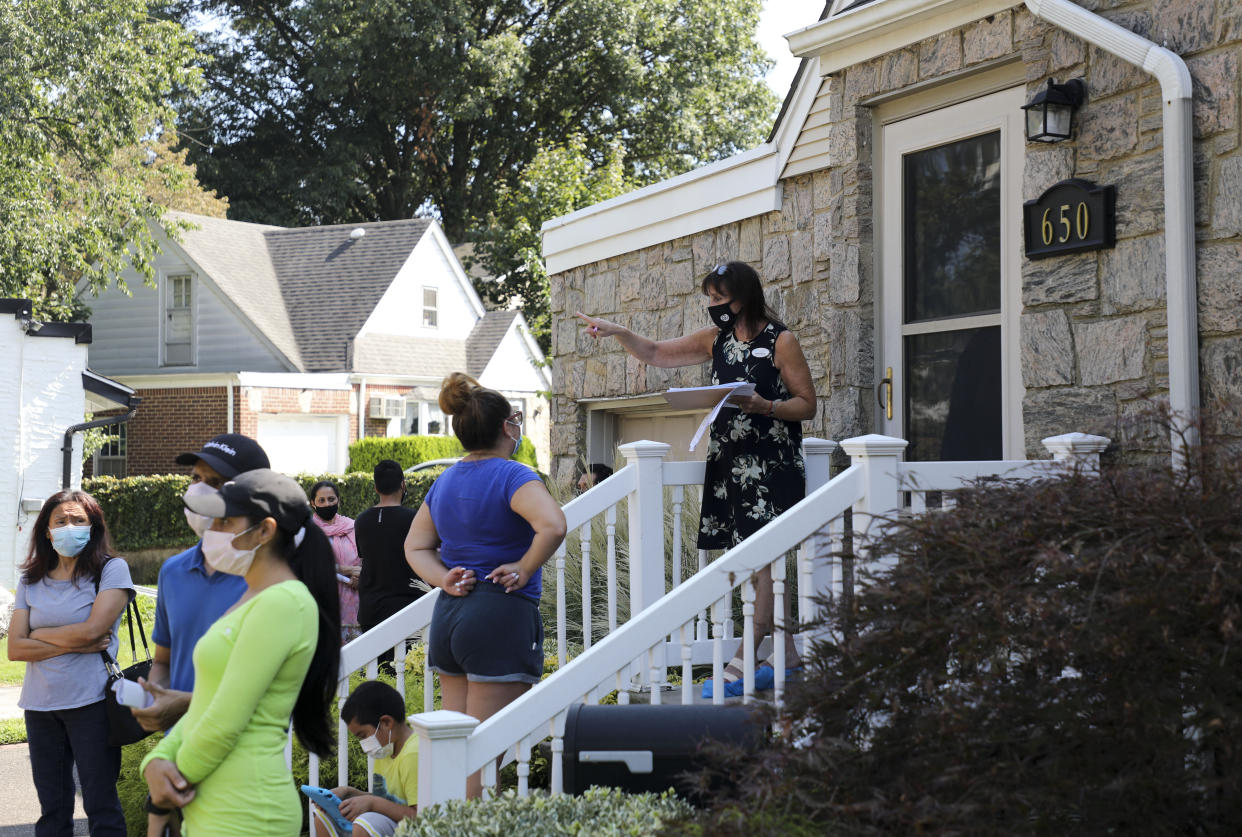 Robin Azougi 1st R, a licensed real estate salesperson with Douglas Elliman Real Estate, talks with prospective buyers at a house for sale in Floral Park, Nassau County, New York. (Credit: Xinhua/Wang Ying via Getty Images)