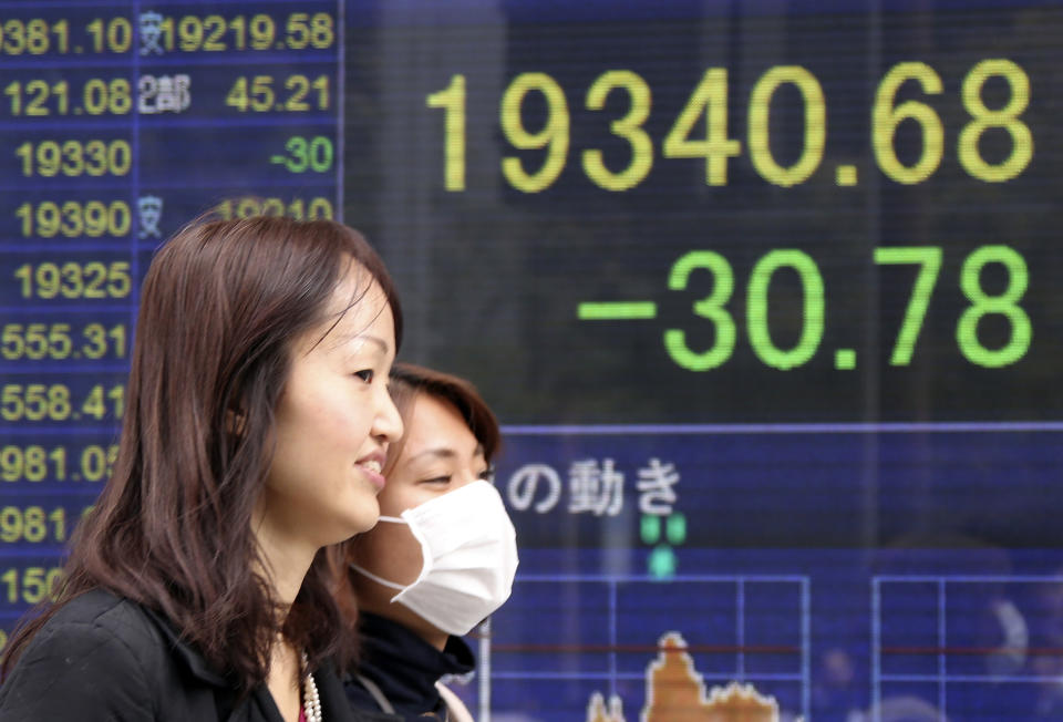 People walk by an electronic stock board of a securities firm in Tokyo, Friday, Feb. 24, 2017. Asian markets slipped in muted trading Friday amid worries over U.S. trade policies that may affect regional economies. A stronger yen weighed on Japan's exporters. (AP Photo/Koji Sasahara)