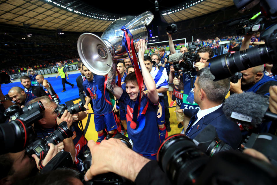 Barcelona's Lionel Messi is surrounded by photographers as he celebrates with the UEFA Champions League trophy.