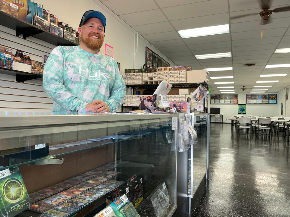 Mom's Basement Games owner Joshua Warren stands behind a counter filled with game cards in Howell on Monday, July 17.