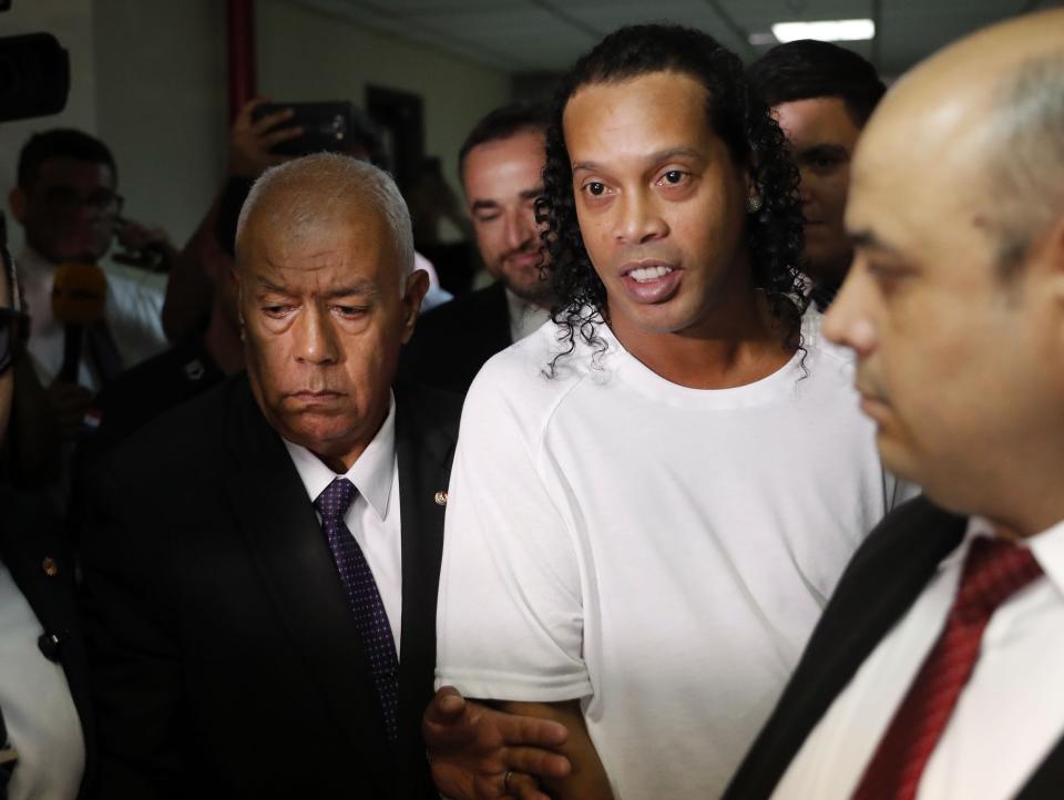 Former soccer star Ronaldinho is escorted by police to go before Judge Mirko Valinotti at the Justice Palace court in Asuncion, Paraguay, Friday, March 6, 2020. Ronaldinho has been detained by Paraguayan police for allegedly entering the country with a falsified passport. (AP Photo/Jorge Saenz)