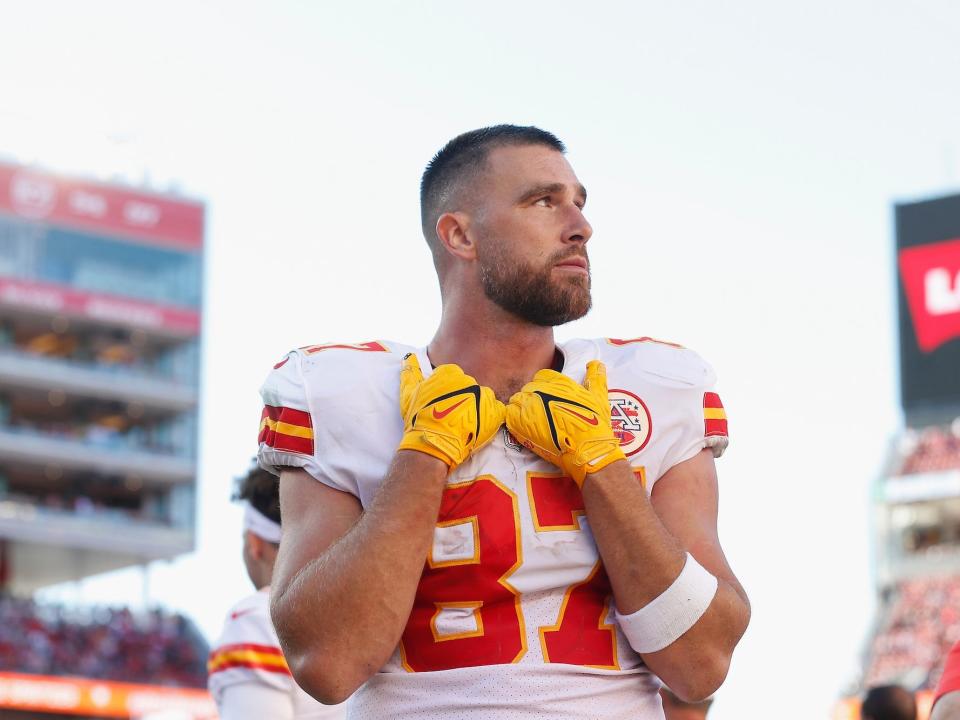 Travis Kelce rests his hands on his collar while looking off to the side during a Chiefs game.