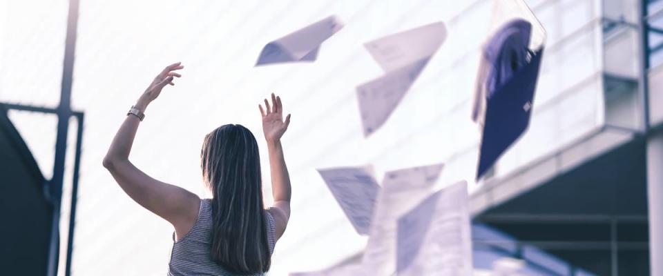 Woman throwing papers in air after quitting job
