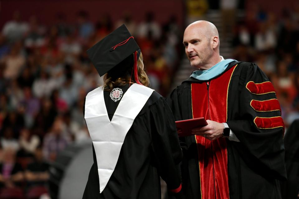 Greenville High School principal, Jason Warren, hands off diplomas during the commencement ceremony that was held at Bon Secours Wellness Arena on Tuesday, May 21, 2024.