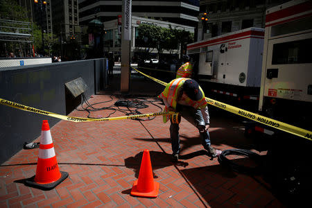 A Bay Area Rapid Transit (BART) worker pulls a caution tape near two generators above Montgomery station during a major power outage in San Francisco, California, U.S., April 21, 2017. REUTERS/Stephen Lam
