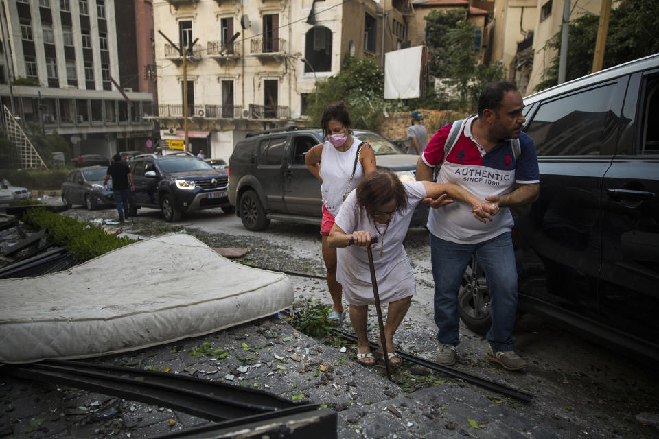 An elderly woman is helped while walking through debris after the explosion. | Daniel Carde—Getty Images