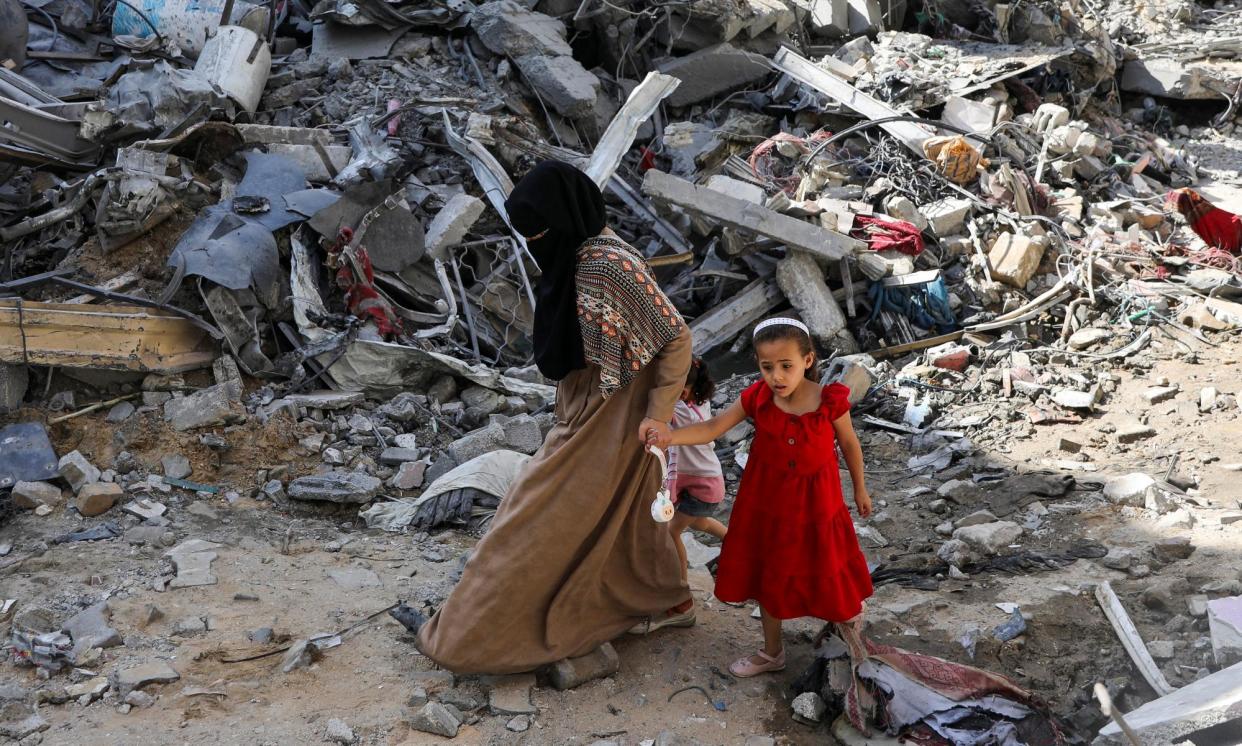 <span>A woman and child walk among debris, in the aftermath of Israeli strikes on Nuseirat refugee camp.</span><span>Photograph: Abed Khaled/Reuters</span>