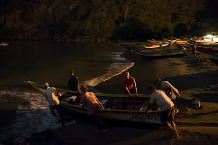 Men push a boat in the bay of Rio Caribe, a town near caribbean islands, in the eastern state of Sucre, Venezuela October 30, 2015. REUTERS/Carlos Garcia Rawlins